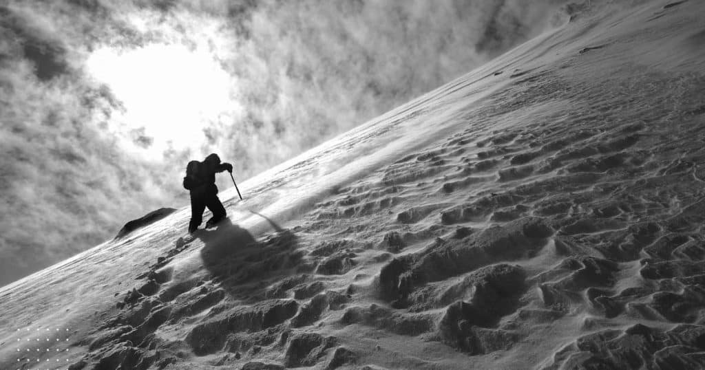 Man summiting a mountain - describing the pain and effort it takes to aim for a problem free live. Nearly impossible.