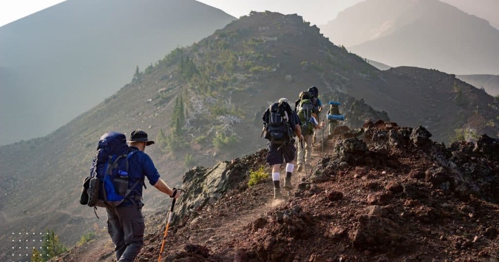 Men summiting a mountain in a group - describing the pain and effort it takes to aim for a problem free live. Nearly impossible.