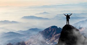 Man hands up on mountain with an incredible view